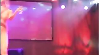 Nude damsel is playing her cooch on the stage, in front of many crazy men